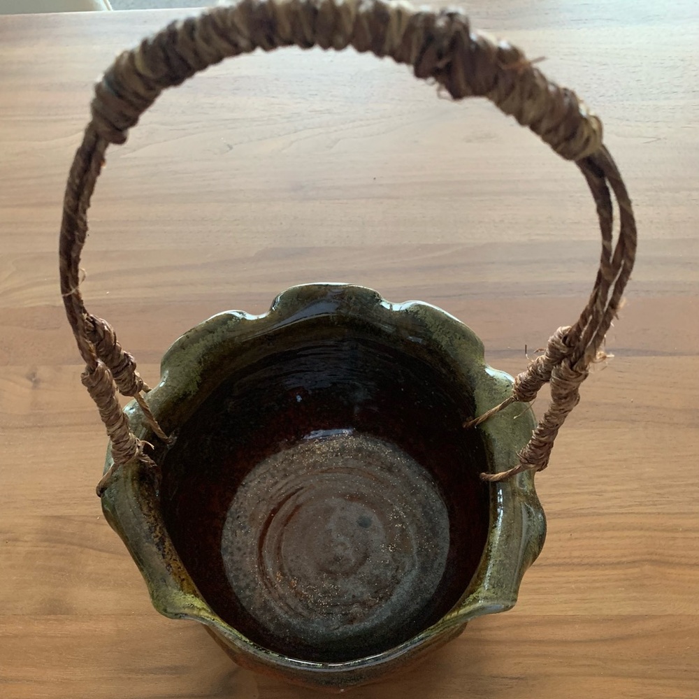 Handmade ceramic ‘basket’ w/ woven handle. Rich glazed, rolled edge, open front.